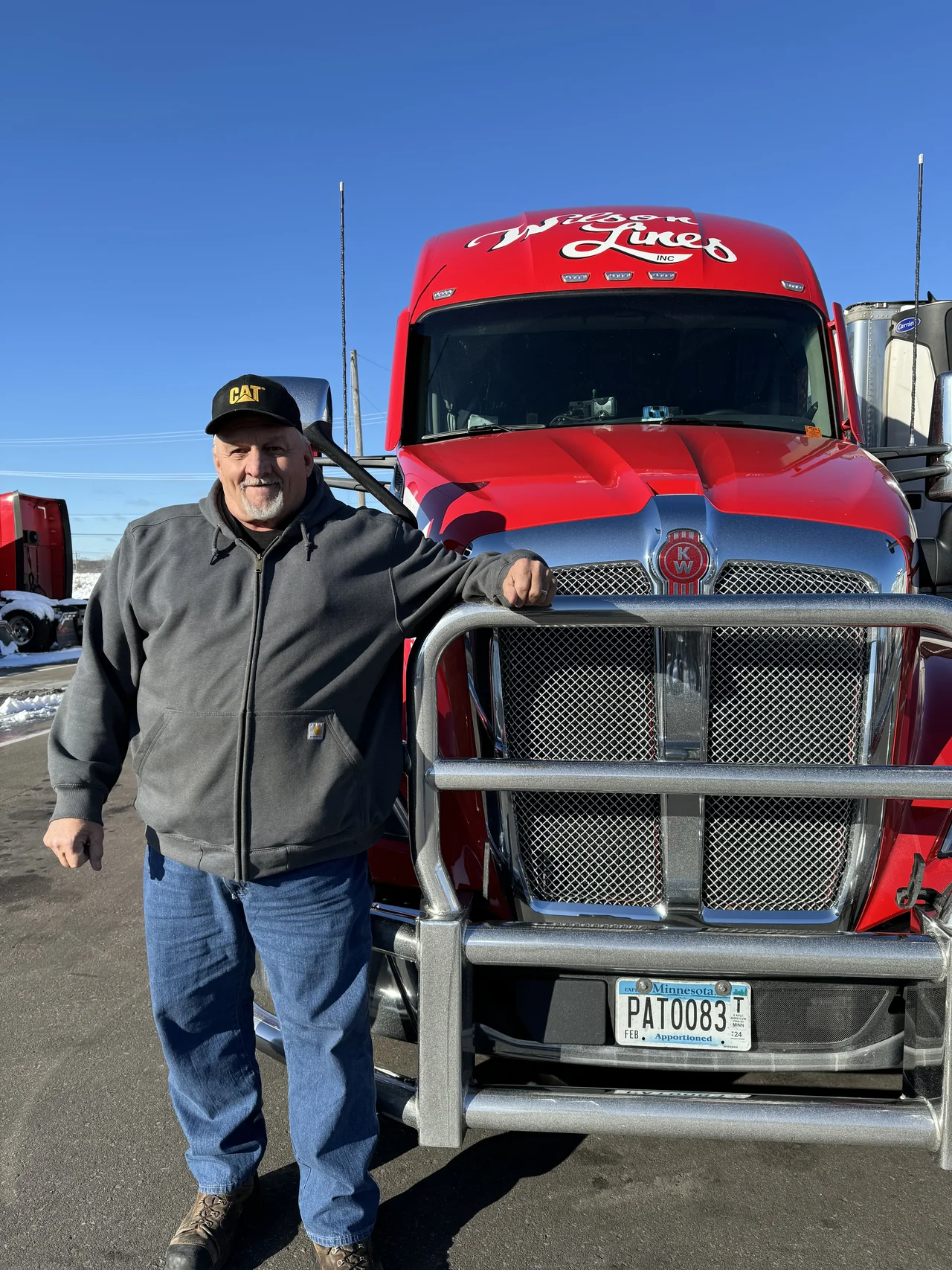 A Wilson Lines driver standing beside a red Wilson truck